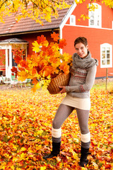 Schöne junge Frau mit Korb voller Herbstlaub in Schweden