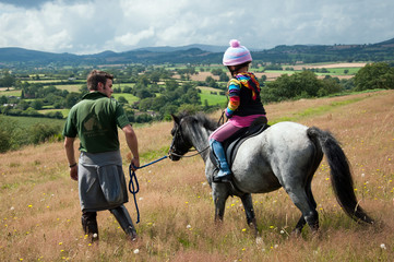Leading pony & young girl in countryside