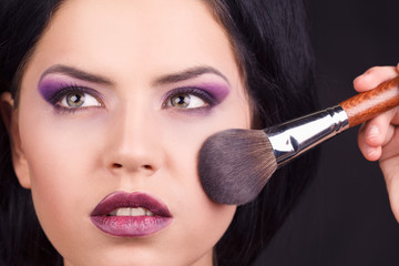 Obraz premium Portrait of the beautiful woman with makeup brushes near face