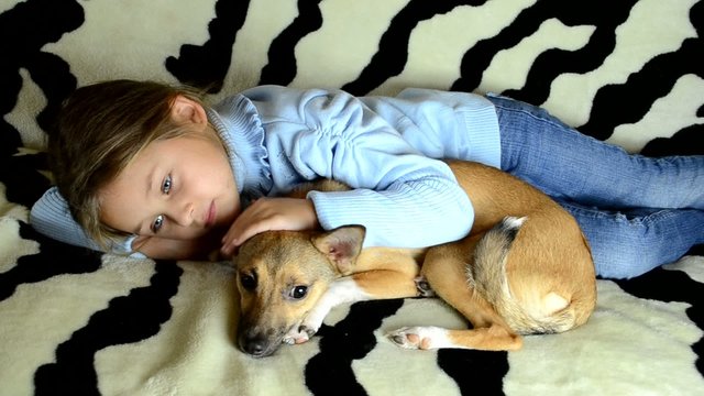 little girl gently hugs and pats a puppy