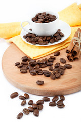 Cup with coffee beans and a bunch of cinnamon on a wooden board.