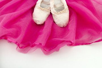 Ballet shoes of a girl on a pink ballet skirt
