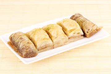 Sweet baklava on plate on bamboo mat