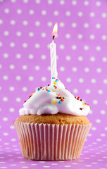 tasty birthday cupcake with candle, on purple background