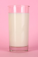 Glass of fresh new milk on pink background