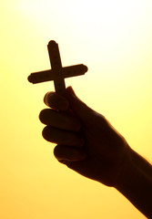 man hand with crucifix, on yellow background.