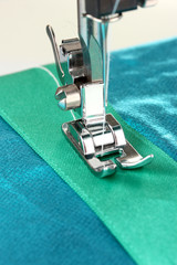 Closeup of sewing machine working part with  blue cloth