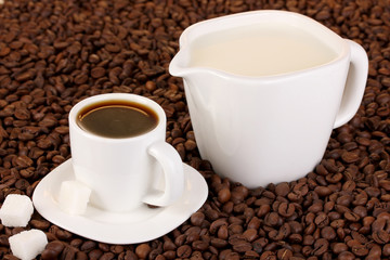 A cup of strong coffee and sweet cream on coffee beans close-up