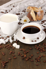 A cup of strong coffee and sweet cream on wooden table close-up