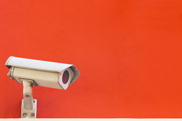 Security camera on a red wall background.