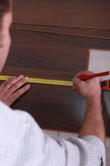 Man measuring slat of parquet