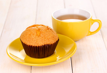 Fresh muffin with tea on wooden background