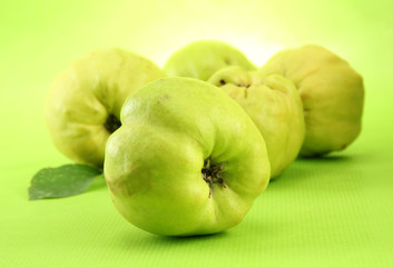 sweet quinces with leaves, on green background