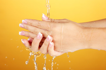 Washing woman's hands on orange background close-up