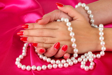 Female hands holding beads on color background