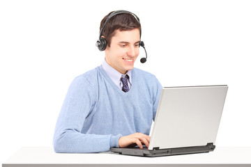 A male operator wearing headset and working on a laptop