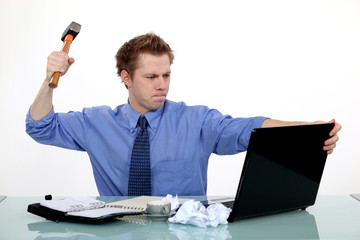 businessman ready to smash his laptop with a hammer