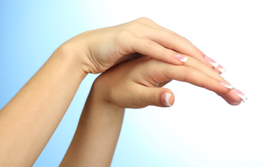 Beautiful woman hands with french manicure, on blue background