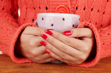 hands holding mug of hot drink, close-up