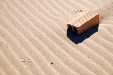 LADRILLO EN LA ARENA DE LA PLAYA