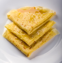 Pancakes with honey on white plate