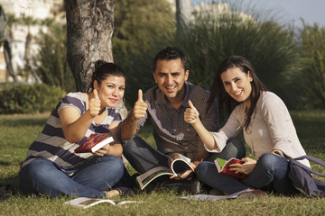 Fototapeta premium Young students studying outdoors thumbsup