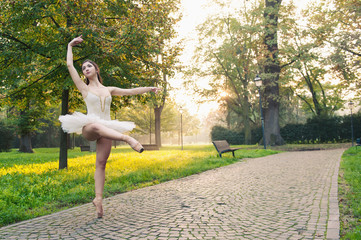 Young beautiful ballerina dancing outdoors in a park.