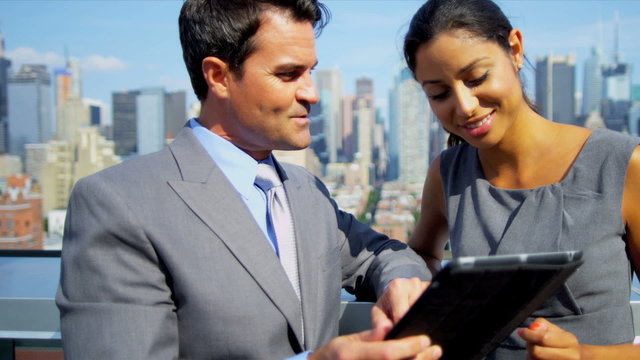Caucasian and Hispanic business team working on tablet on rooftop 
