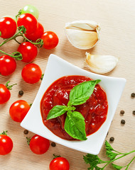 Red tomato sauce in a pan and ingredients
