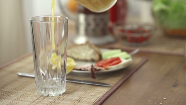 Pouring orange juice in glass, slow motion shot at 240fps