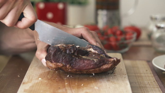 Hand cutting block of ham with knife, slow motion
