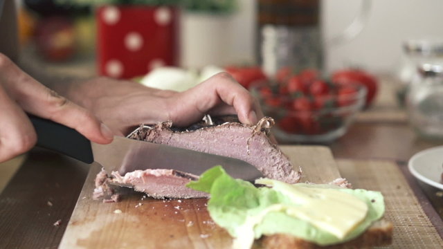 Hand cutting ham and preparing sandwich, slow motion