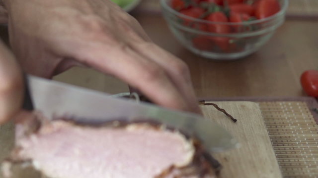 Hand cutting block of ham with knife