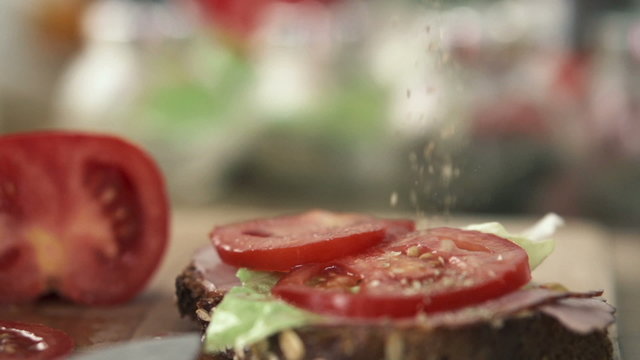 Hand sprinkle spices on tasty sandwich, slow motion shot at 240f