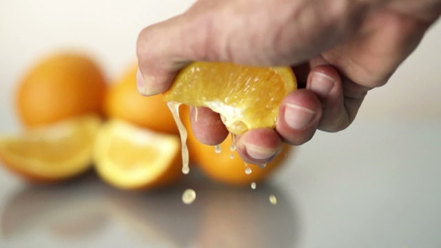 Hand squeeze juicy orange, slow motion shot at 480fps
