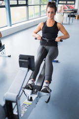 Fototapeta na wymiar Woman training hard on row machine