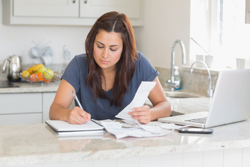 Obraz na płótnie Canvas Woman calculating receipts with laptop