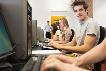 Fototapeta na wymiar Uczniowie siedzą w sali komputerowej z mężczyzna uśmiecha