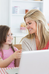 Daughter pointing at laptop with mother
