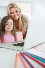 Fototapeta na wymiar Mother standing behind daughter looking at laptop