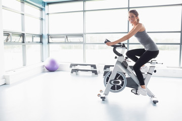 Happy woman riding an exercise bike