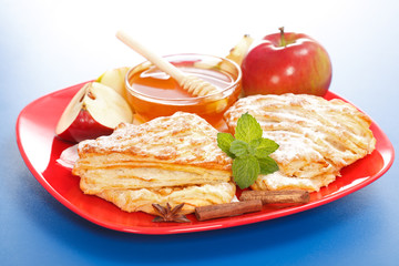 Apple cakes on plate, honey and apple pieces around