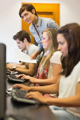 Students sitting at the computer with teacher looking on