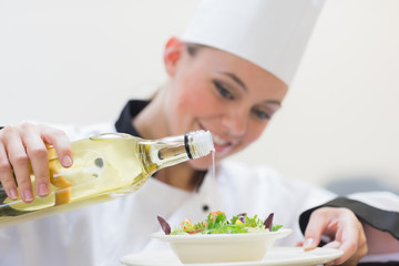 Smiling woman chef dressing a salad