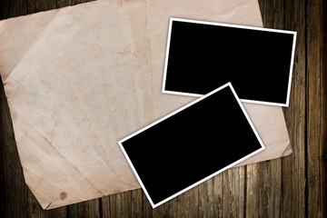 Aged paper and photo frames on a wooden background