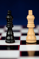 Black and white queen standing at the chessboard against blue ba
