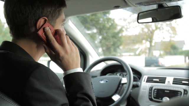 Young man driving car and talking on the phone