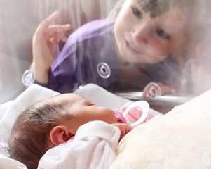 Obraz na płótnie Canvas Noworodka dziewczynka w inkubatorze. Jej siostra patrzy.