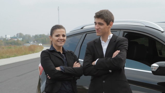 Portrait of young businesspeople next to car