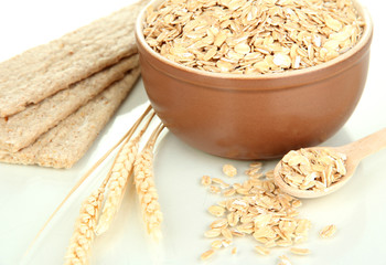 Brown bowl full of oat flakes with spikelets, oat biscuits and